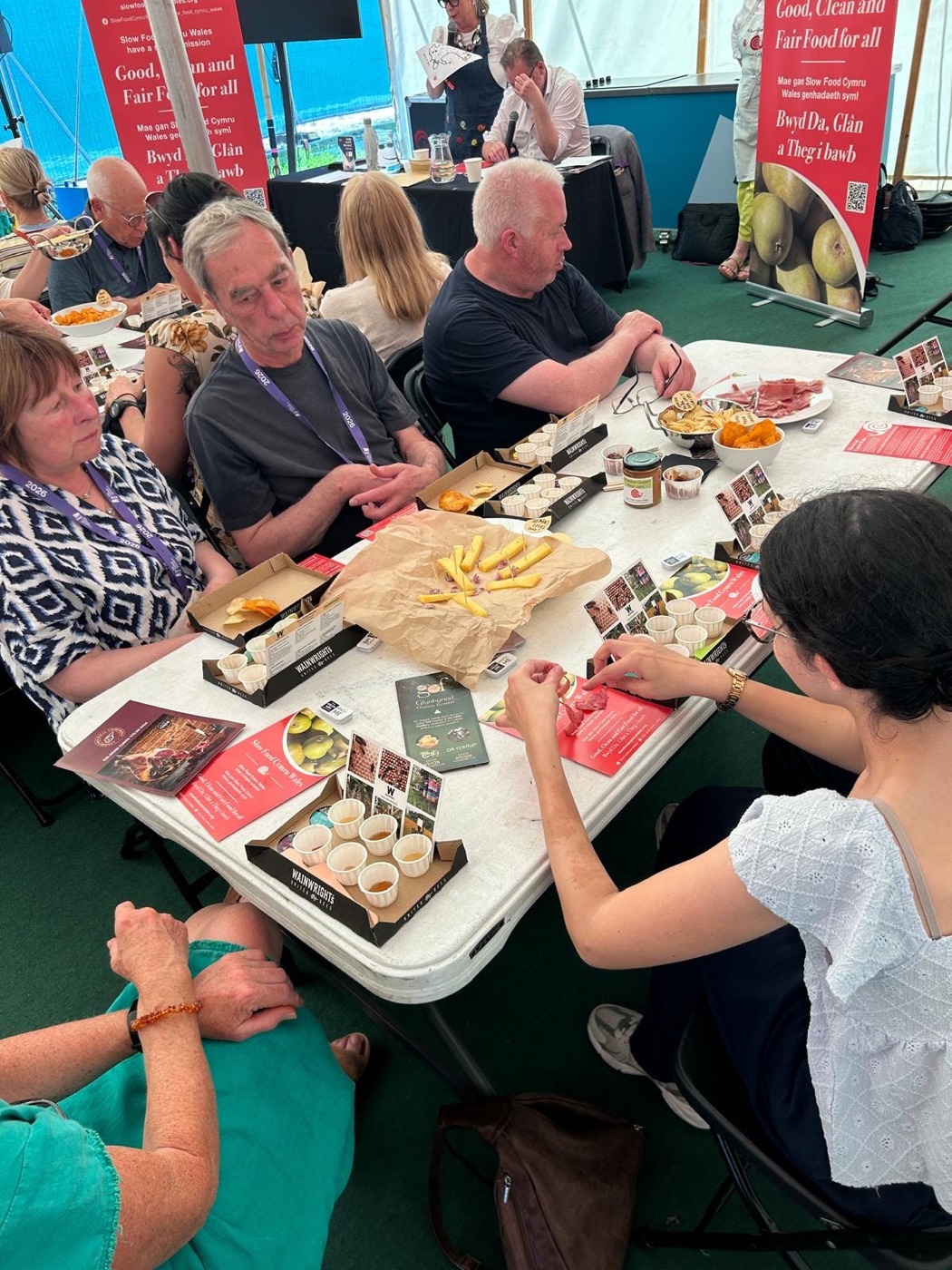 Festival-goers around a table of tasting platters and Slow Food leaflets